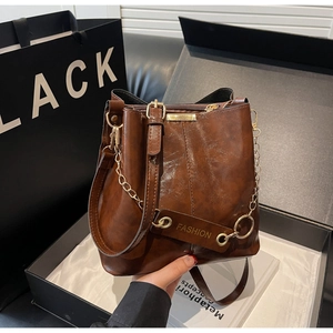 Detail of dark brown vintage bucket bag with oil wax finish and gold chain in gift box