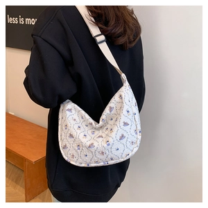 Rear view of a floral white half-moon canvas shoulder bag with adjustable strap