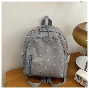 Detailed macro view of floral print backpack with front pocket and durable nylon texture