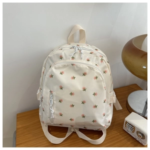Close-up of floral pattern canvas backpack with front zipper pocket on wooden surface