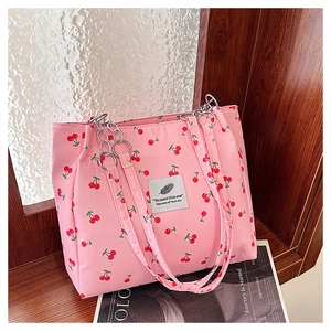 Detailed view of pink tote bag with cherry print and metallic chain shoulder strap