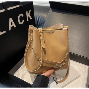 Detail of tan leather bucket bag with gold chain strap and fashion hangtag accents