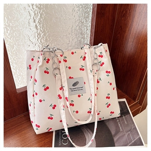 Detail of cherry print canvas tote bag with metal chain strap on vintage wood shelf