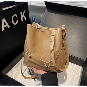 Detail view of khaki bucket bag with golden chain and fashion tag in a premium gift box