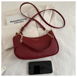 Detail of burgundy pebbled leather handbag with gold lettering and metal chain strap
