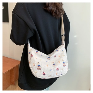 Detail of quilted beige half-moon bag with colorful circus print and adjustable strap