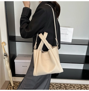 Detail of beige lychee pattern bucket bag featuring FASHION stamped text and wide strap