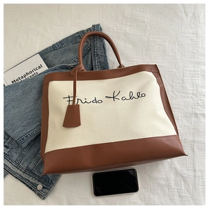 Close-up of canvas tote bag with Frida Kahlo signature and leather trim details