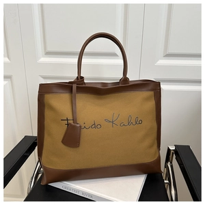 Close-up of canvas and brown leather tote bag with Frida Kahlo embroidery detail