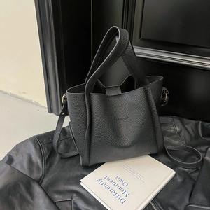 Detail of black pebbled leather bucket bag with embossed FASHION text on a leather background