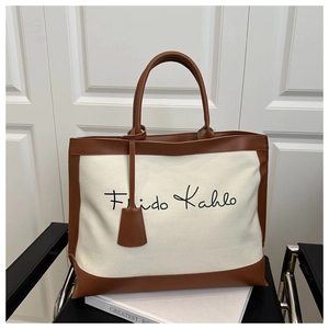 Detail of canvas tote bag featuring leather trim and Frida Kahlo script on the front