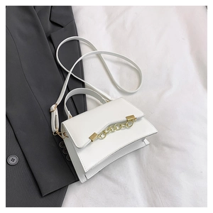 Close-up of white leather handbag with wave edge design and golden chain detail
