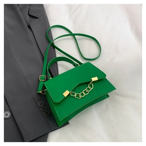 Macro view of bright green leather handbag with gold chain detail and flap closure