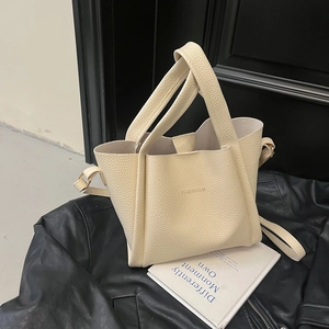 Detail of off-white lychee pattern bucket bag featuring minimalist FASHION text design