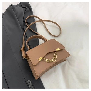 Detail of khaki shoulder bag with gold chain strap on soft white fabric background