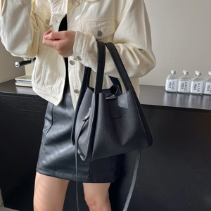 Minimalist black lychee leather bucket bag with top handle and shoulder strap for daily use