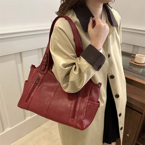 Sac fourre-tout rouge foncé à fermetures éclair sur modèle en trench-coat beige