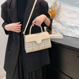 Sac à main crème gaufré à carreaux avec bandoulière porté sur un costume noir