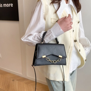 Chic black leather crossbody bag with bold gold chain detail worn by a model
