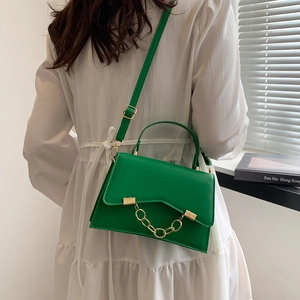 Vibrant green leather handbag with chunky gold chain detail and adjustable strap