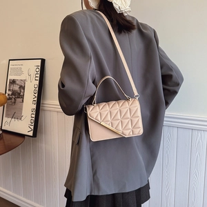 Borsa a tracolla trapuntata beige con fibbia dorata indossata da modella in giacca