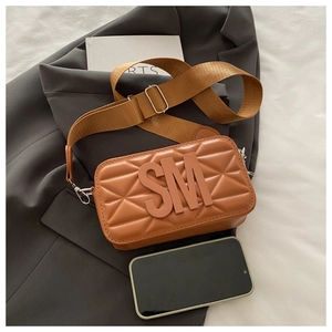 Detail of brown quilted camera bag with embossed SM logo and wide fabric strap
