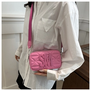Detail of pink quilted camera bag featuring SM metal logo and wide fabric strap
