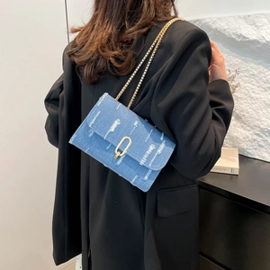 Blue denim crossbody bag with gold chain strap and distressed frayed fabric finish