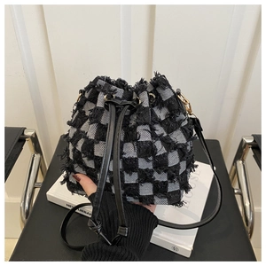 Detail of checkered tweed bucket bag with black leather drawstring and gold hardware