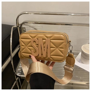 Close-up of khaki crossbody bag featuring quilted texture, SM logo, and wide shoulder strap