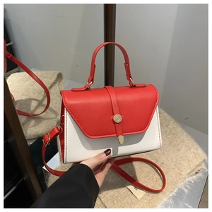 Detail of red and white contrast handbag featuring gold circular buckle and red strap
