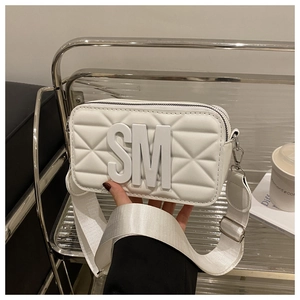 Detail view of white quilted crossbody bag with bold SM logo and wide nylon shoulder strap