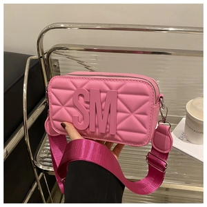 Detail of pink quilted camera bag with bold SM 3D letters and wide nylon shoulder strap
