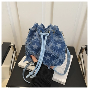 Detailed shot of star patchwork embroidery and frayed denim edges on the bucket bag