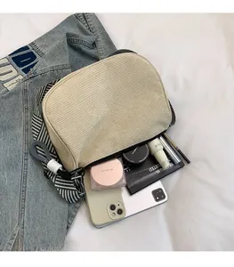 Internal storage detail of beige corduroy bag showing phone and cosmetics items