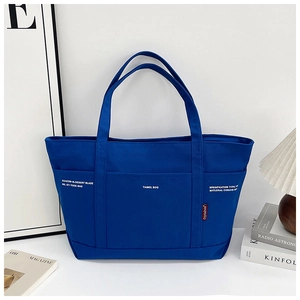 Detailed front view of navy canvas tote bag with functional pockets and white print