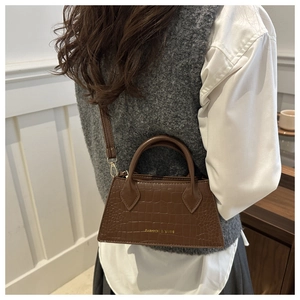 Detail of dark brown crocodile-embossed handbag with gold lettering for women