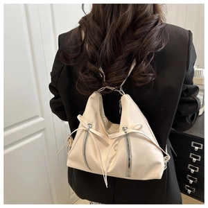 Creamy white shoulder bag featuring a stylish bow detail and double zipper on the model