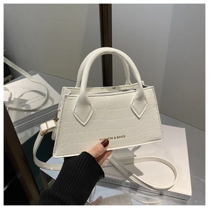 Detail of white crocodile pattern texture and golden logo on fashion handbag