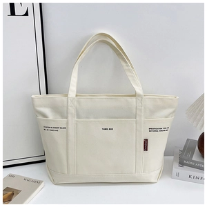 Detailed view of white canvas tote bag with front pocket and aesthetic side red label