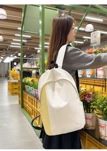 Side view of white and yellow canvas backpack featuring embroidered Y logo in a floral shop