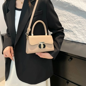 Elegant beige leather handbag with gold T-clasp hardware and adjustable crossbody strap