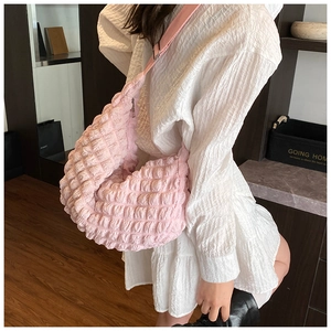Detailed view of pink bubble textured crossbody bag with metal zipper and matching strap