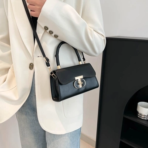 Classic black leather handbag with gold buckle and top handle shown on a model