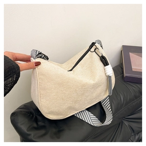 Close-up of beige corduroy shoulder bag showing ribbed texture and striped strap detail