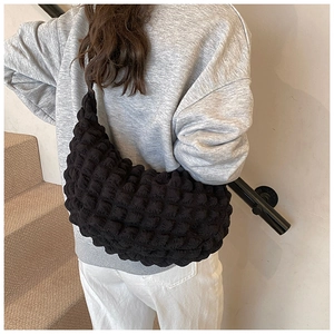 Detail of a black popcorn texture shoulder bag shown on a model for a casual look