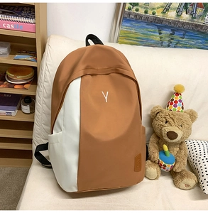 Detail view of water-resistant nylon backpack with asymmetrical caramel and white color blocking