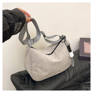 Detail of grey corduroy crescent bag with a decorative white knot on the zipper pull