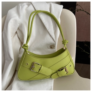Detail of avocado green baguette bag with belt buckle straps on white blazer