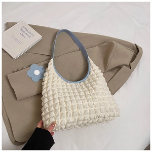 Detail of pleated white shoulder bag with blue leather strap and floral charm accessory